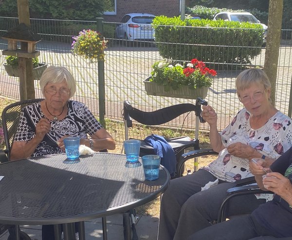 Zwei Seniorinnen sitzen auf einer Terrasse und essen ein Eis.