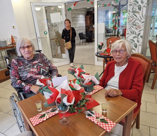 Zwei Seniorinnen sitzen an einem schön gedeckten Tisch mit italienischer Dekoration.