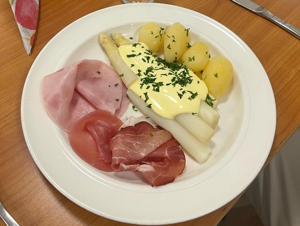 Auf dem Bild sieht man einen Teller mit Spargel, Kartoffeln, Sauce Hollandaise und verschiedenen Sorten Schinken