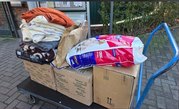 Das Bild zeigt oben zwei Frauen und einen Mann, die in die Kamera schauen. Unten ist ein Wagen mit Kartons, Tüten und Wolldecken.