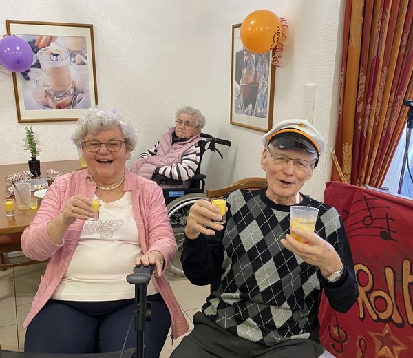 Ein älteres Ehepaar prostet mit Eierlikör. Der Mann trägt eine Kapitänsmütze, beide lachen in die Kamera.