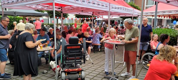 Sommerfest im Freien mit Bierzeltgarnituren und Pavillons. Menschen sitzen zusammen, essen und trinken. Bunte Luftballons und Wimpel schmücken das Festgelände.